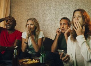 Disappointed heterosexual couples watching sports together at night