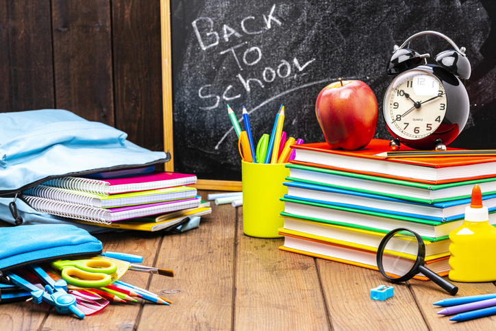 Back to school: multicolored school supplies shot on wooden desk.