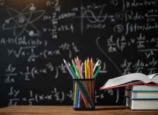 Back to school supplies. Books and blackboard on wooden background,education