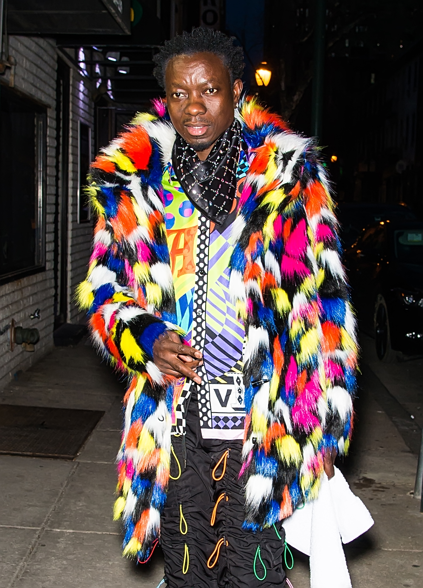Michael Blackson in hair tie pants and colorful shirt