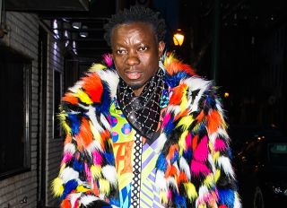 Michael Blackson in hair tie pants and colorful shirt