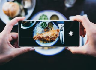 Woman photographing fish and chips in a restaurant with a smartphone