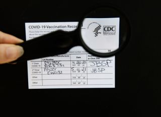 An authentic Covid-19 vaccination card, with CDC logo in magnifying glass