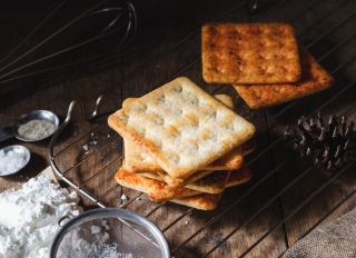 Square Dry Crackers Biscuit On A Wooden Table. Wooden Texture Dark Background. Snack Dry Biscuits