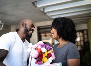 Husband surprising his wife with a flowers and present at home