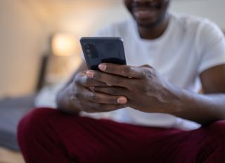 Young man text messaging while sitting on bed at home