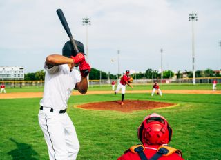 Rear view of baseball batter and catcher watching the pitch
