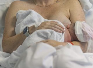 Newborn baby lying skin to skin on mother's chest moments after being born