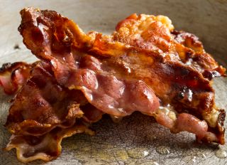 A stack of crispy rashers of bacon in a pan