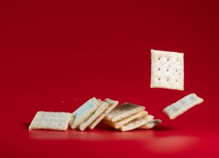 flavored soda cracker flying in mid air in red background