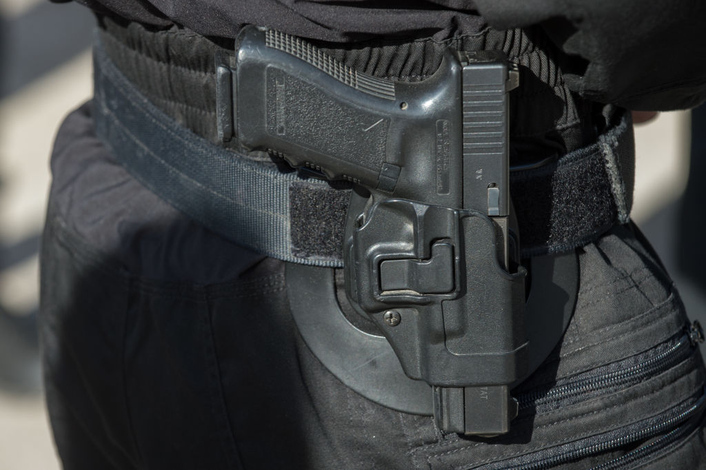 A Glock pistol seen in close-up hanging from the belt of a...