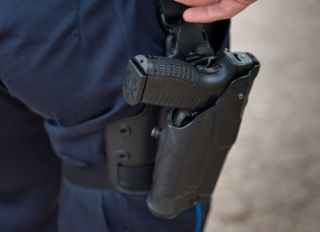 A policeman's gun seen in close-up attached to the belt...