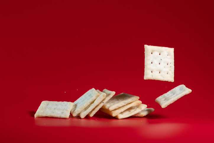 flavored soda cracker flying in mid air in red background