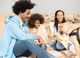 Happy Afro family and their dog enjoying during a family picnic at the beach