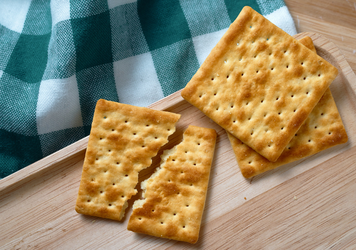 Cracked wholegrain cracker on the wooden tray