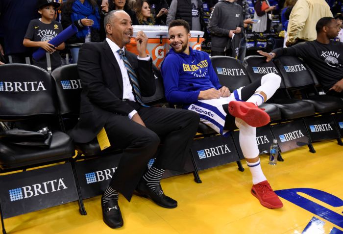 Dell Curry chats with his son Golden State Warriors' Stephen Curry (30) while sitting on the sideline before the start of their NBA game against the Charlotte Hornets at the Oracle Arena in Oakland, Calif. on Friday, Dec. 29, 2017. (Jose Carlos Fajardo/Ba