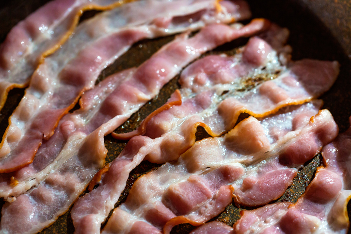 Slices of fresh fried bacon in a pan.