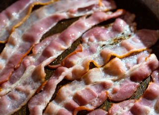 Slices of fresh fried bacon in a pan.