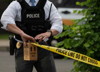 A police officer pulls police tape after a shooting in a...