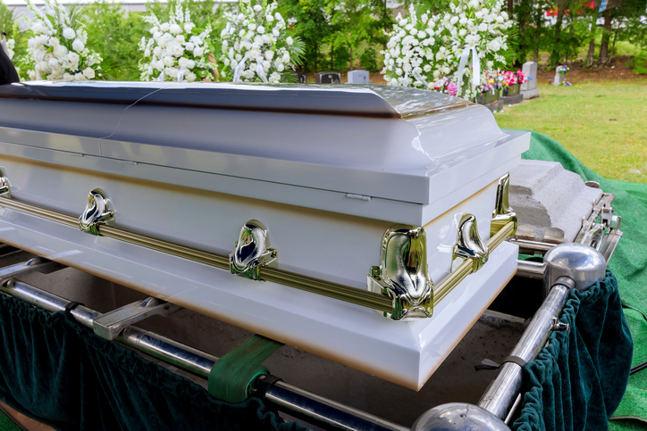 Funeral service in cemetery with coffin on elevator system of automatic sinking into grave