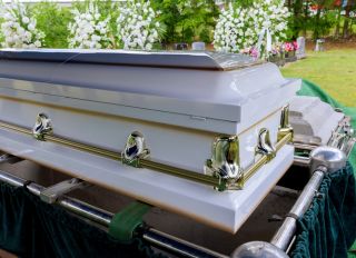 Funeral service in cemetery with coffin on elevator system of automatic sinking into grave