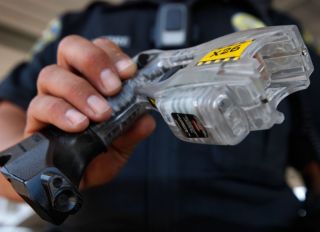Police officer George Aguirre holds a Taser fitted with a video camera (lower left) in Brentwood, Calif., on Wednesday, July 21, 2010. The camera is activated every time police officers aim the electric stun gun