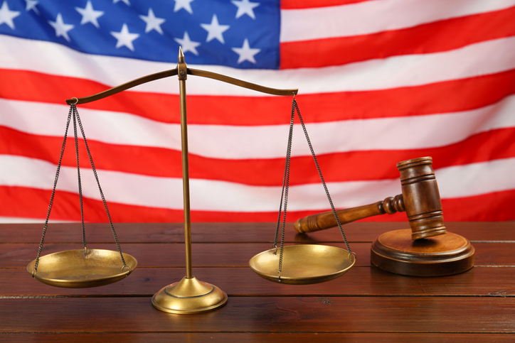 Scales of justice and gavel on wooden table against American flag