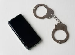 Handcuffs and Mobile Phone on the Wooden Table closeup. right to call when arrested or detained by the police