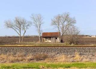 Old western cowboy house under cultivation and next to the railroad track in texas.