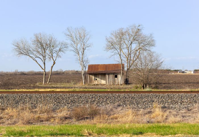 Old western cowboy house under cultivation and next to the railroad track in texas.