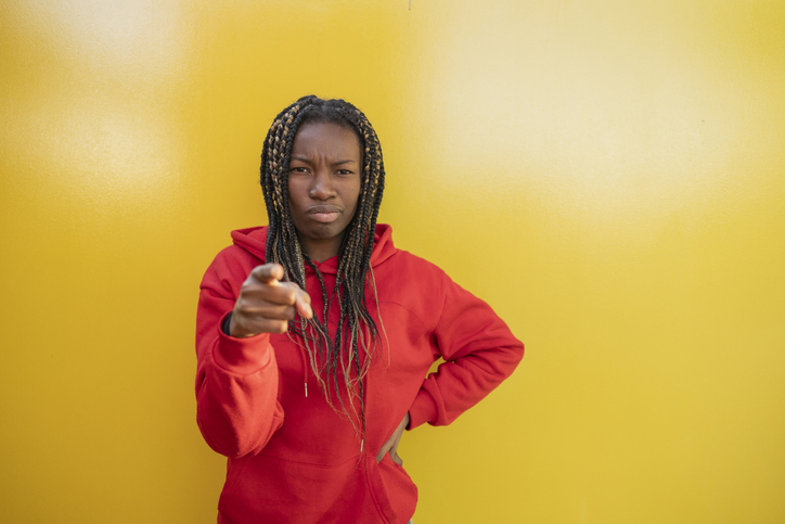 african woman pointing suspicious face yellow background