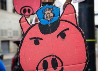 A pig sign with a police hat is seen during the...