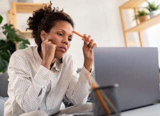 Young African ethnicity businesswoman sitting in front of laptop computer calculating expenses