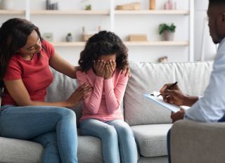 African american girl crying during therapy session with child psychologist