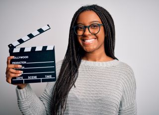 Young african american director girl filming a movie using clapboard