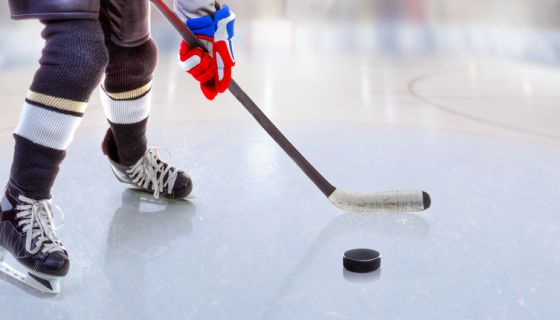 Close up of ice hockey player with stick on ice rink controlling puck