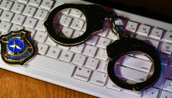 Concept of cybercrime and cybersecurity with keyboard, handcuffs, and police badge
