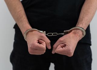 Men's hands closed in chrome handcuffs