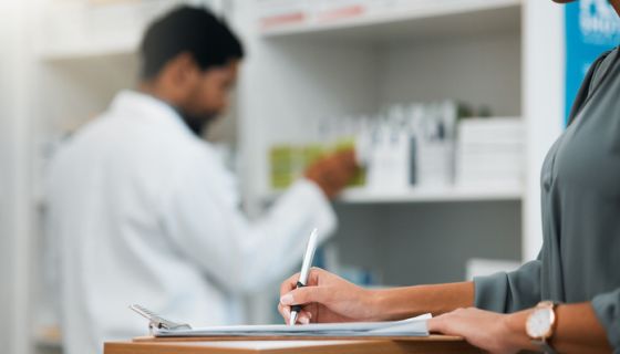 Woman at pharmacy, clipboard and medical insurance information at counter for script for prescription medicine. Paperwork, writing and patient at pharmacist with application for pharmaceutical drugs.
