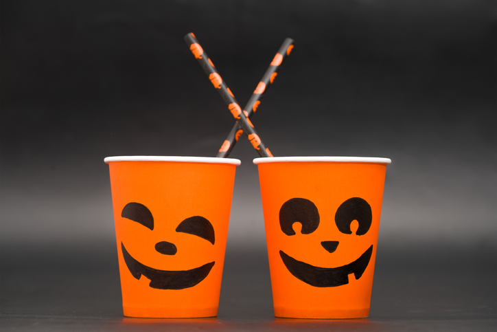 Halloween coffee paper cup with pumpkin faces on black background. Concept for coffee house