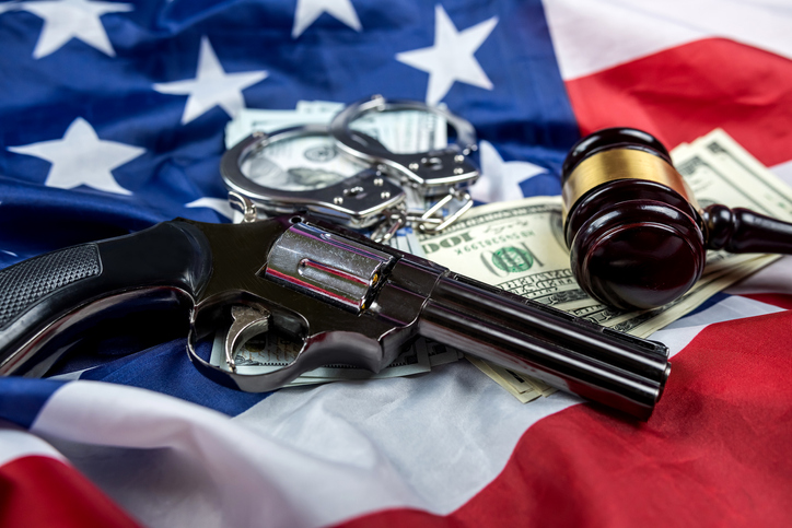 Gavel handcuffs and money dollars and a gun on the background of American flag of the USA.