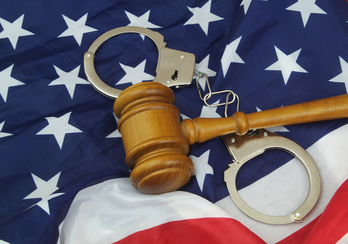 Judge wooden gavel and handcuffs on US flag.