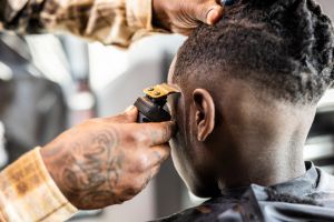 Barber cutting young boys hair in barbershop - closeup
