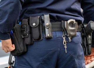Policeman, police equipment utility belt with a gun, pepper spray and various accessories, detail shot, closeup seen from behind Police officer tools simple concept, emergency services job, occupation