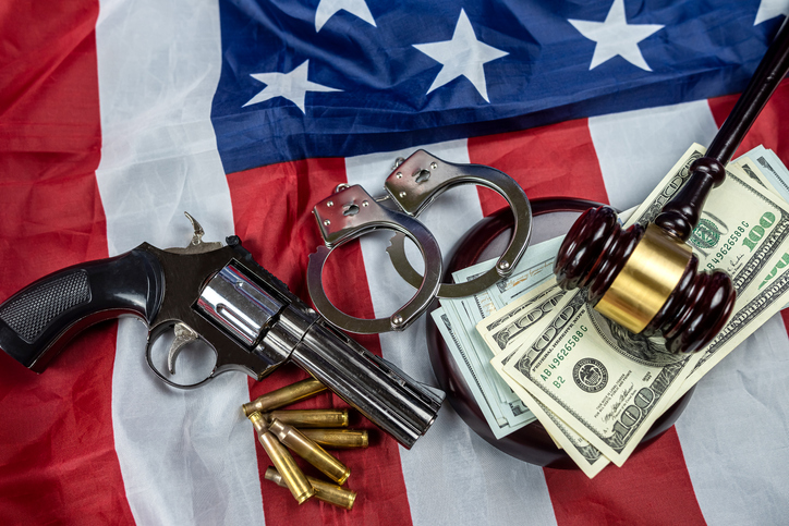 Gavel and handcuffs and money and gun on the background of the American flag of the USA.