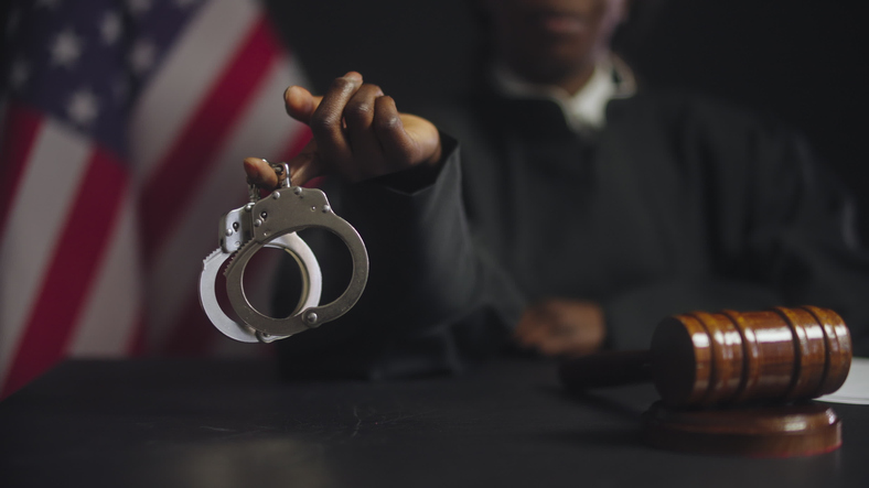 Black female judge showing handcuffs on camera, punishment for criminals, law