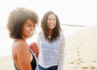 Happy female friends looking away while standing at beach