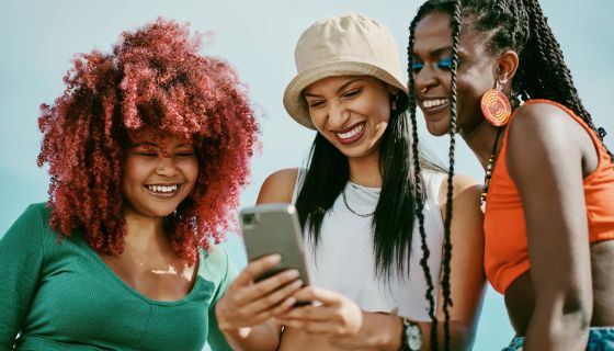 Shot of a group of young friends using a phone in the city - stock photo