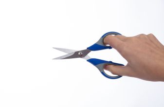 woman holding a pair of scissors on a white background, scissors on hand