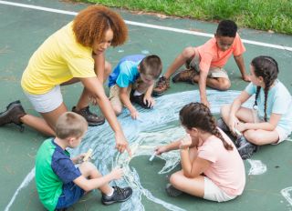 Camp counselor with children, chalk drawing of earth